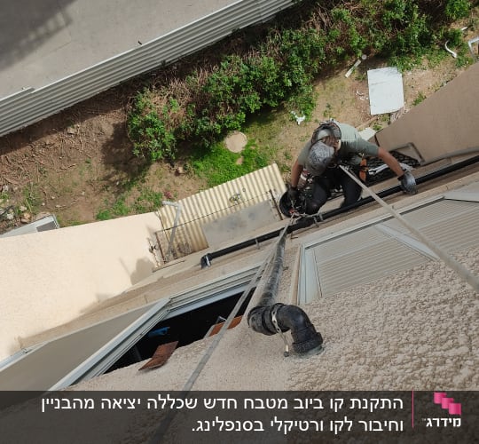 אדם עם ציוד טיפוס ליד צינור על קיר חיצוני